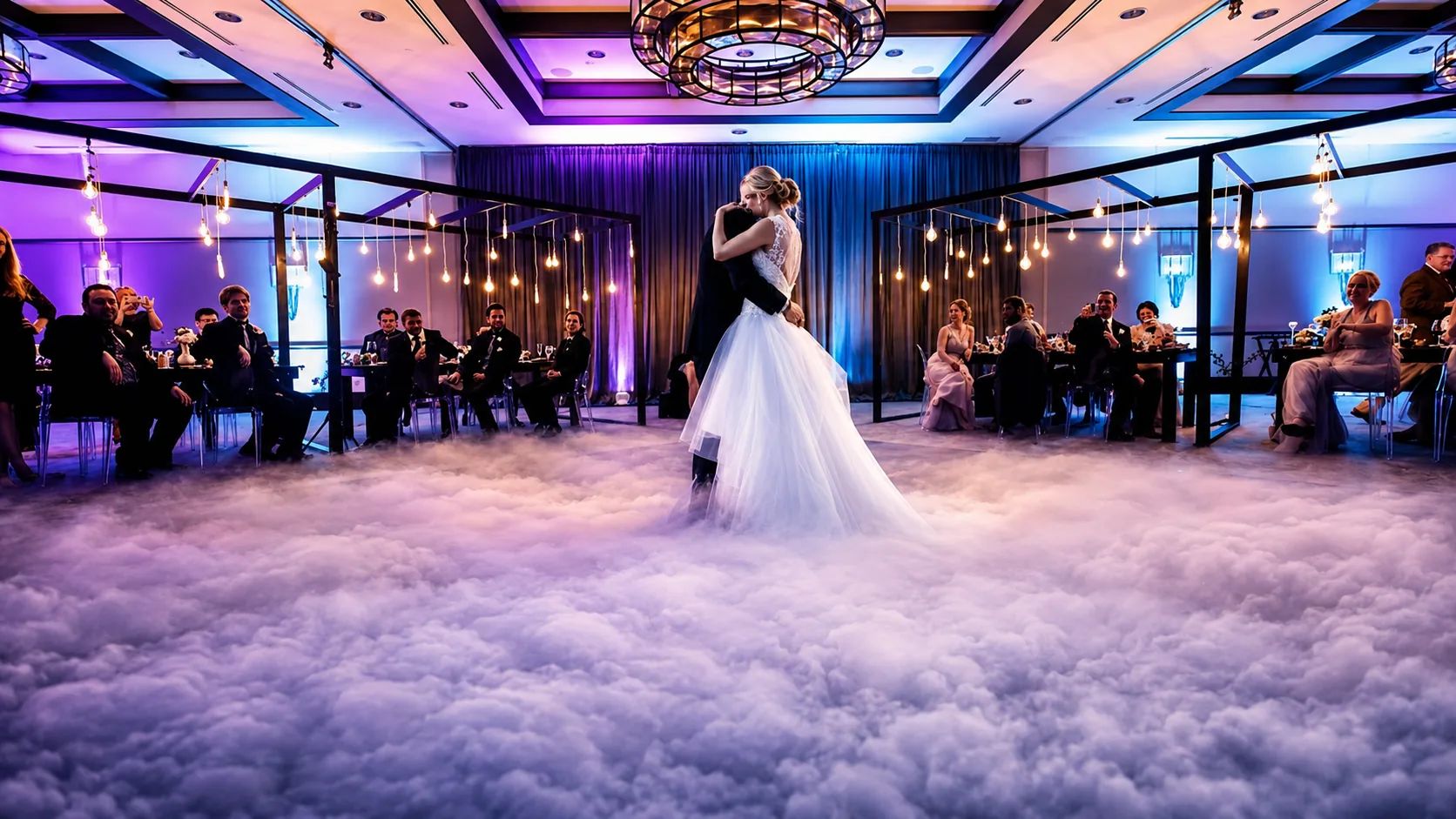 Bride and groom sharing a first dance on a cloud of low-lying fog under dramatic uplighting