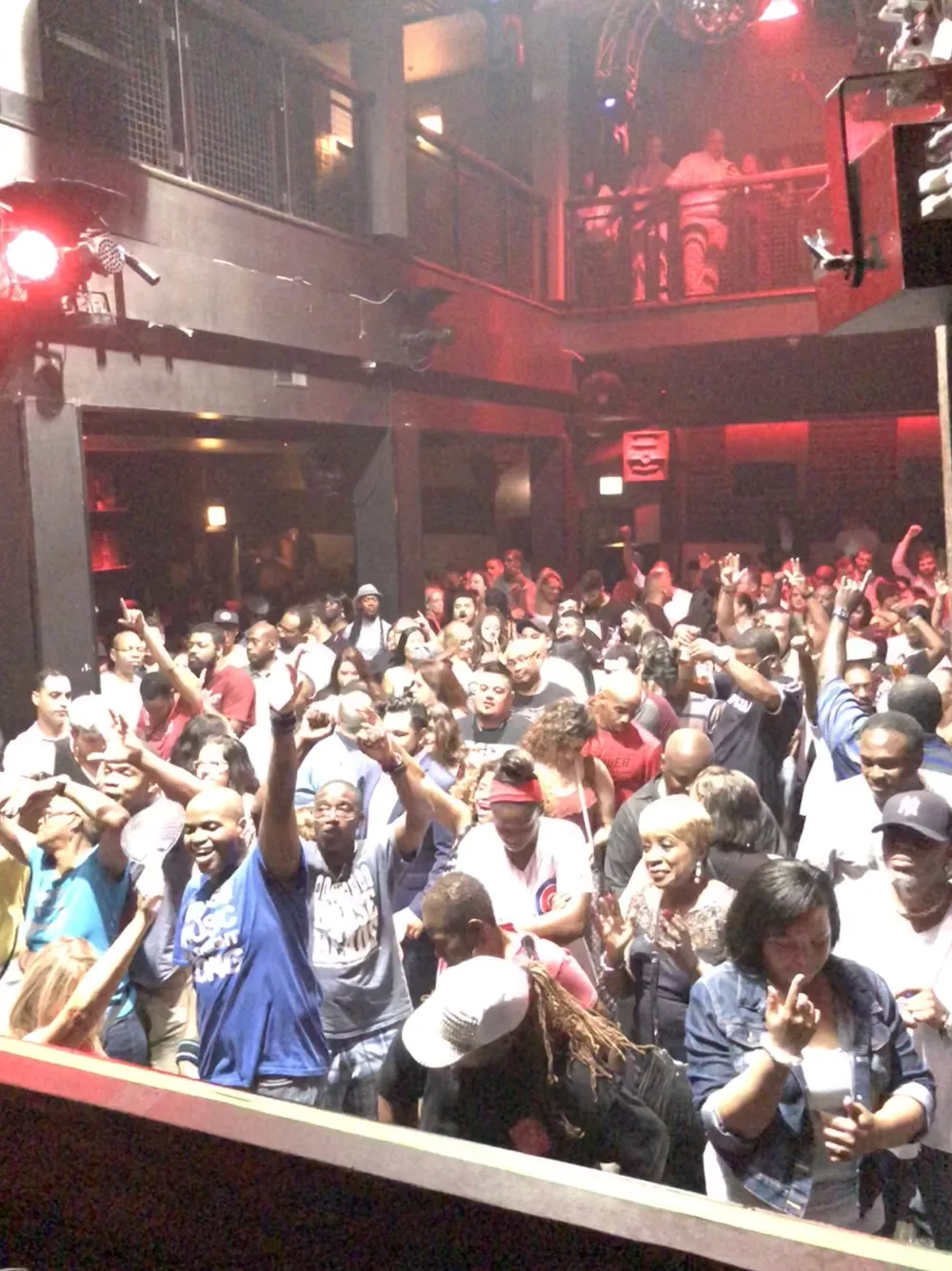 Packed nightclub crowd dancing under red lights at a Hot Mix event