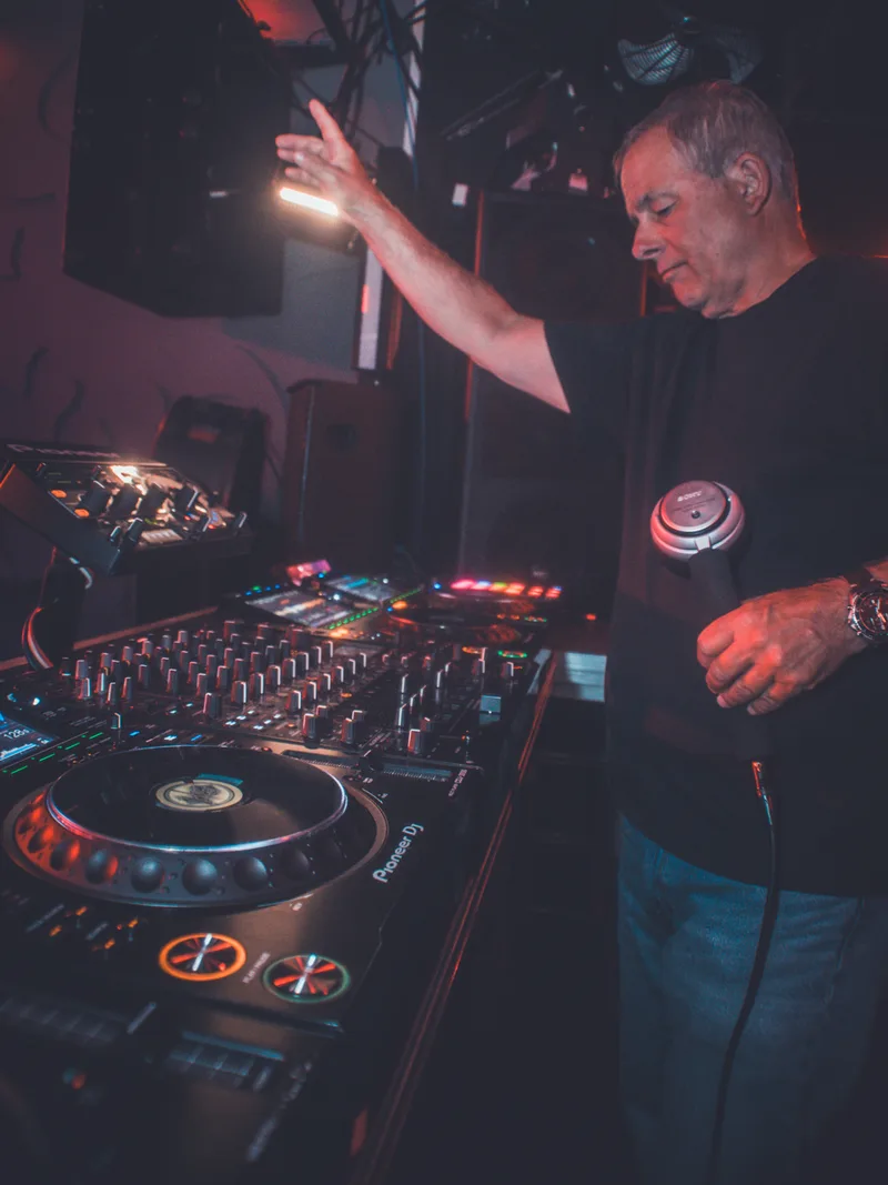 Scott Smokin Silz with hand raised mixing on Pioneer CDJs in a dark nightclub