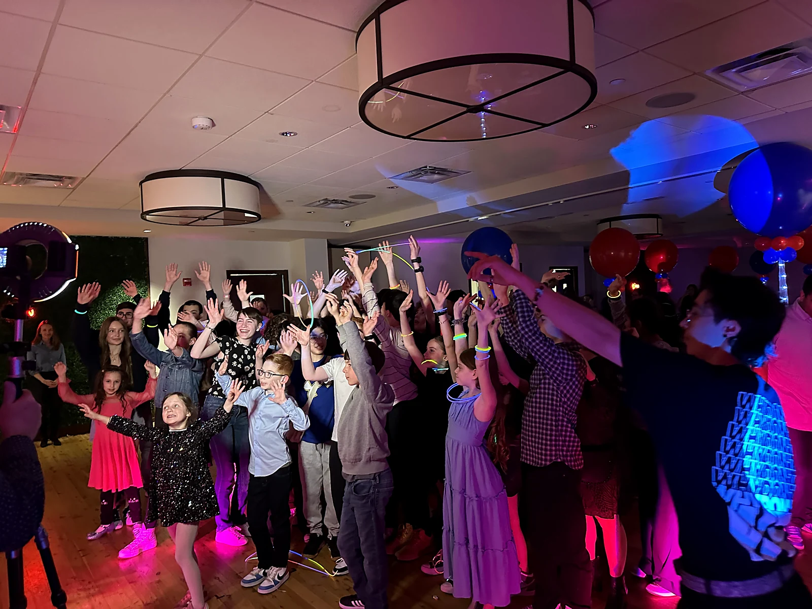 Young guests dancing and cheering at a private celebration with blue and red lighting