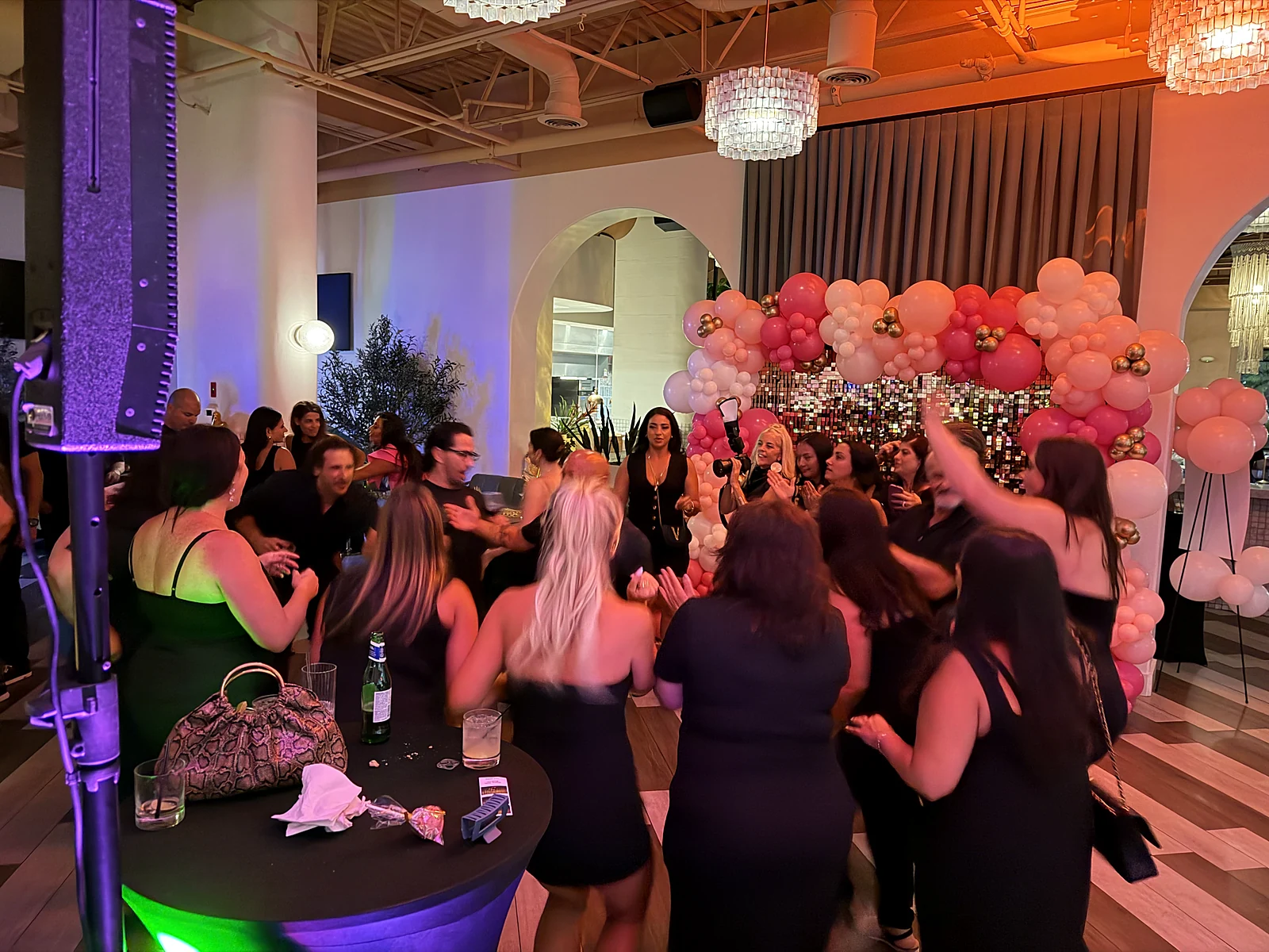 Women dancing together surrounded by pink balloons at a birthday party