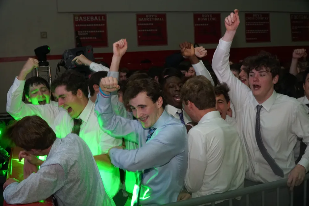 Group of students celebrating under green laser lighting at a school dance