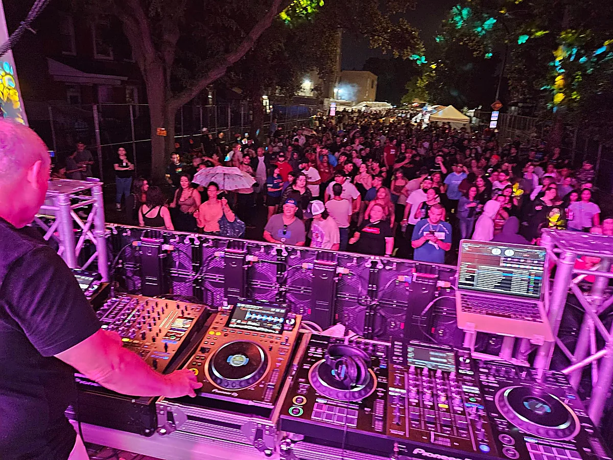 Scott Smokin' Silz DJing an outdoor festival with a massive crowd dancing under purple lighting
