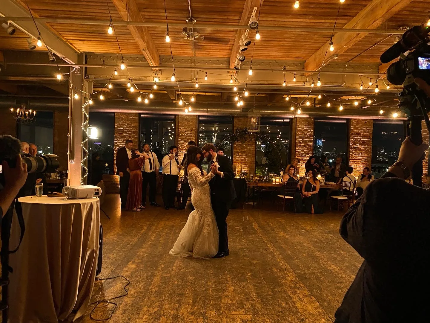 Bride and groom sharing their first dance in a Chicago loft venue under warm string lights